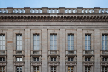A frontal view of a neoclassical-style building with symmetrical columns, rectangular windows, and...