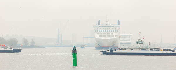 Warnemunde , Germany - March 31, 2024.  Big modern Skane  Siena line ferry ship navigate from Rostock harbor bay foggy spring morning misty weather. Maritime traffic passenger cargo vessel Baltic sea