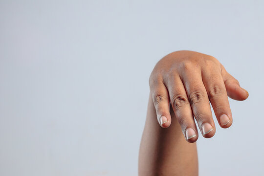 Relaxed human hand hanging downward with fingers gently drooping expressing calm gesture or passive body language against plain background