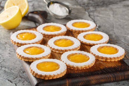 Shortbread cookies with lemon crud filling sprinkled with powdered sugar closeup on wooden board on the table. Horizontal