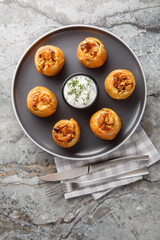 Knish or knysh is a traditional food of Eastern European consists of a filling covered with dough that is baked closeup on the plate on the table. Vertical top view from above