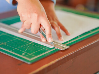 Closeup hand female using cutter to cut the paper in classroom at school. Lifestyle Concept...