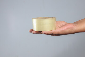 Transparent packing tape roll held in hand used for packaging, shipping, sealing