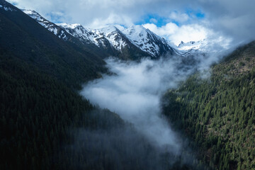 Aerial view of beautiful high altitude snow capped mountain and forest landscape