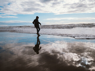 Person Enjoying a Stroll by the Ocean Waves at Beach