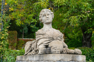 Massandra Palace of Emperor Alexander III. Stone sphinx statue with human head and lion's body, set against lush green garden backdrop. Sphinx appears contemplative. Yalta, Crimea - September 30, 2019