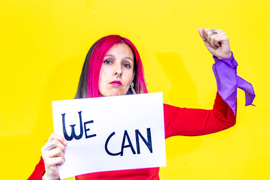 Woman showing we can sign and raising fist on yellow background