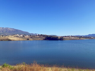 Obraz premium Scenic View Over Farka Lake Hills. A calm and scenic view over Farka Lake in Tirana, surrounded by olive trees, hills, and peaceful countryside atmosphere. Farka Lake view Tirana Albania.