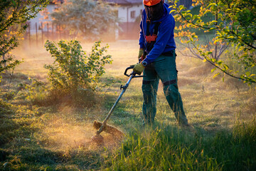 man mowing the grass with a lawn mower. Garden work at sunset