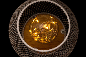 Garland inside a light bulb on a metal mesh background, warm light, decoration