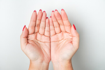A woman's hand with bright red nail polish is making an open hand gesture and praying. Isolated on...
