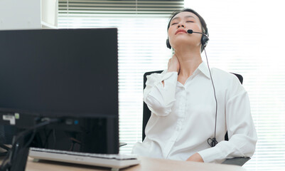Young woman experiencing discomfort while working at a desk in an office setting during the day