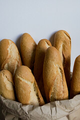 Fresh baguettes in brown paper bag against white background