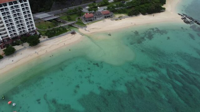4K The serene seascape of Okinawa showcases crystal-clear waters, exposed rocky formations, and gentle waves lapping against the shore