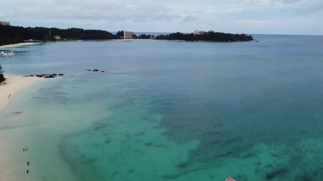 4K The serene seascape of Okinawa showcases crystal-clear waters, exposed rocky formations, and gentle waves lapping against the shore