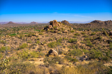 Desert landscape with rocky outcrops, cacti, and a distant view of Scottsdale from Pinnacle Peak Trail in Arizona.