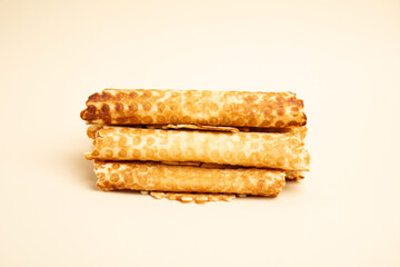 Stack of waffle rolls – front view, beige background, isolated 