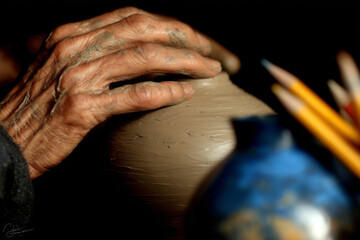 Primer plano de manos moldeando arcilla en torno, símbolo de artesanía y creatividad.