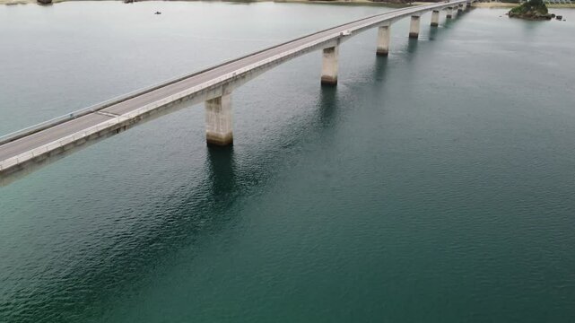 4K focus on road over Long bridge of Kouri Island and beach from a high view by drone with clear sky and sea water.