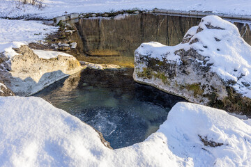 Thermal spring Kaďa in Liptovský Ján, Slovakia. Natural mineral pool surrounded by snowy rocks in the Low Tatras. Winter wellness, healing water, serene landscape, free public access.