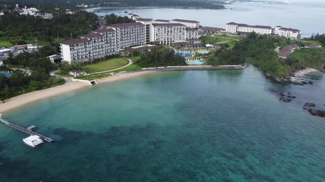 4K over the serene seascape of Okinawa showcases crystal-clear waters, exposed rocky formations, and gentle waves lapping against the shore