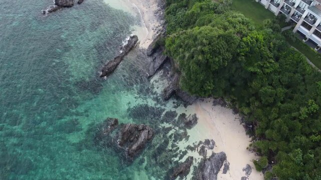4K over the serene seascape of Okinawa showcases crystal-clear waters, exposed rocky formations, and gentle waves lapping against the shore