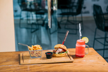 Delicious beef burger with fries and a refreshing drink served on a restaurant table