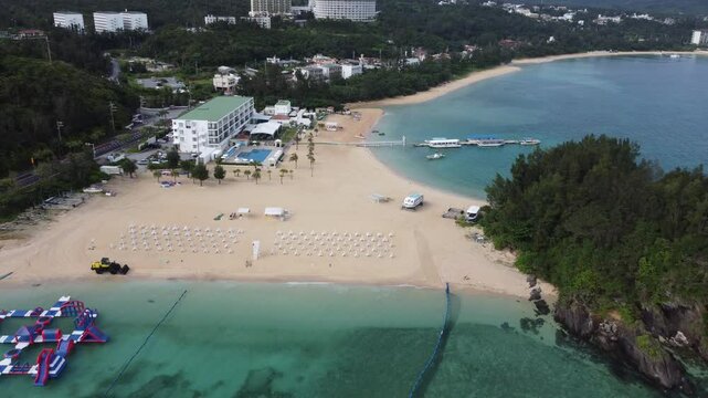 4K over the serene seascape of Okinawa showcases crystal-clear waters, exposed rocky formations, and gentle waves lapping against the shore