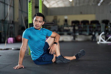 Fototapeta premium Fitness and Recovery. Man in a seated position on gym floor, preparing for stretching.