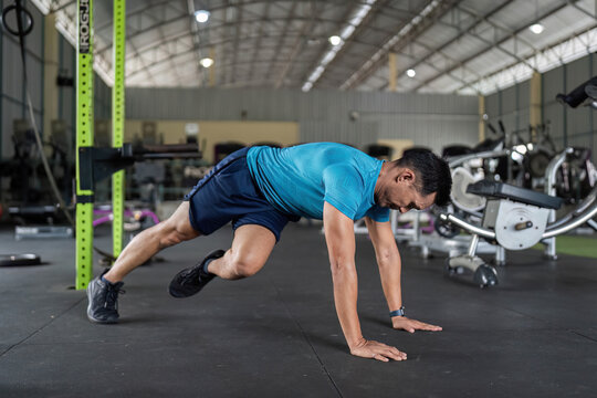 Fitness Cardio Exercise. Man performing mountain climbers in a gym.