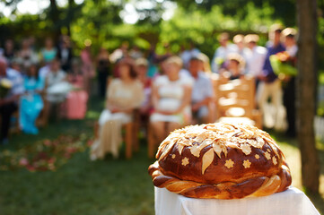 Traditional Wedding Bread Karaway Displayed During Outdoor Celebration with Guests in Background..