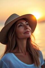 woman in a hat against the backdrop of the sea at sunset.