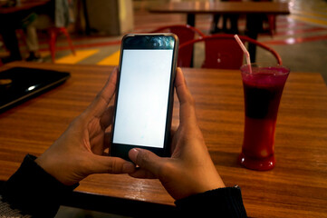 Woman Hand Holding Smartphone With An Empty Screen. A White-Screen Phone Mockup For Display Your Ads. Close-up Image