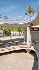 Architectural detail of a circular concrete rump structure with sleek metal railings and a minimalist design used for cyclists and pedestrians to access the promenade in Seville, Spain