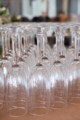 Lots of upside-down champagne flutes neatly arranged on a brown fabric, elegant narrow-stemmed glasses typically used for serving sparkling wine or bubbly during weddings, receptions or upscale events