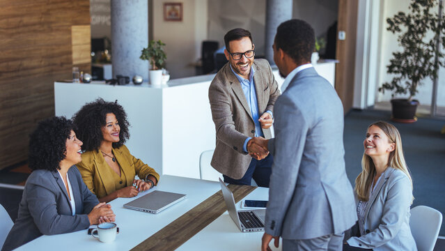 Colleagues Greeting New Team Member with Handshake in Modern Office