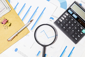 Detailed Market Trend Review – Magnifier Examining Graph with Pen and Calculator on Desk

