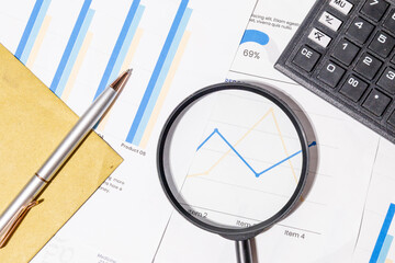 Business Line Graph Under Magnifying Glass – Focused Financial Analysis with Calculator and Pen
