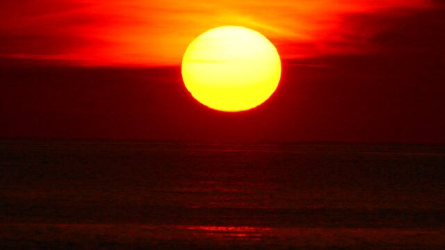Sunset Sun Ocean Landscape: Vibrant red sky, large yellow sun setting over dark ocean, dramatic evening scene.