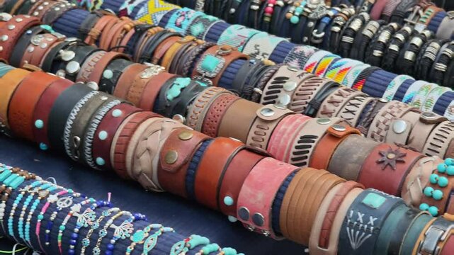 Leather and beaded bracelets displayed on rolls at a crafts market