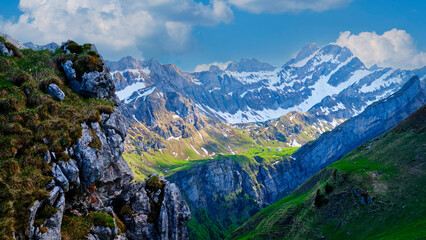 Majestic mountains rise above green valleys under a clear blue sky in a breathtaking alpine landscape