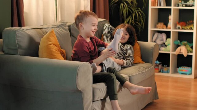Happy siblings tickling and playing on sofa