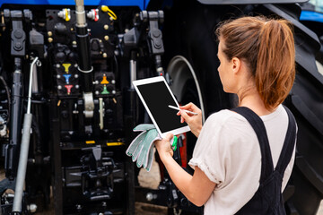 Female mechanic using digital tablet to manage farm equipment repair
