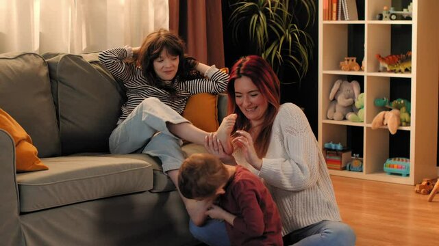 Mother and children tickling feet on sofa in playroom