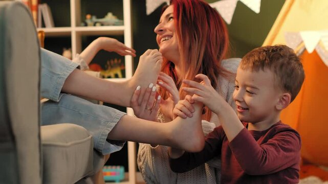 Mother and son sharing a playful foot massage at home