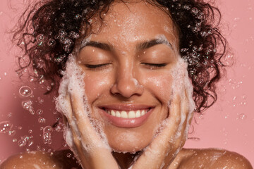 Smiling young woman with curly black hair washing her face with soap and water with closed eyes. Woman holding her face with both hands. Soap bubbles flying around. Healthy glowing skin. Generative AI