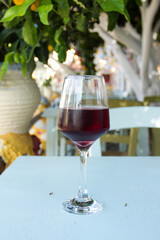 Glass of red wine in a greek restaurant on the terrace. Cold red wine on a hot summer day. A frosty glass of cold wine. Greek restaurant terrace