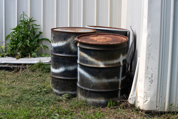 Old rusty steel barrels on the side of a building