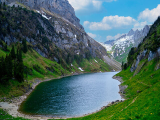 Scenic mountain landscape with a tranquil lake surrounded by lush greenery and snow-capped peaks