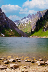 Stunning alpine lake surrounded by mountains in the summer with clear blue skies and lush greenery